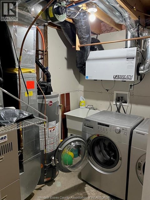 A man is working on a washing machine in a laundry room.