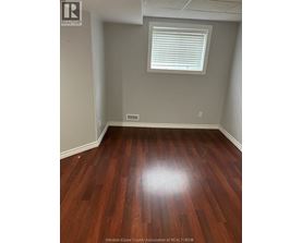 A room with wooden flooring and a window with blinds.