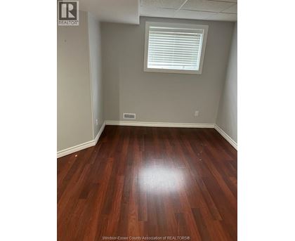 A room with wooden flooring and a window with blinds.
