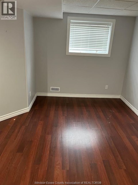 A room with wooden flooring and a window with blinds.