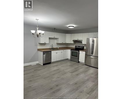 A kitchen with white cabinets and a wooden island.
