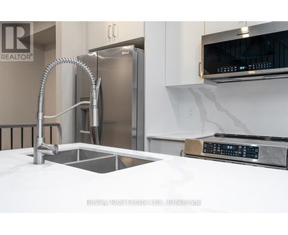 A modern kitchen with a stainless steel refrigerator and a white countertop.