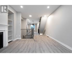 A spacious room with a fireplace and a staircase with a metal railing.