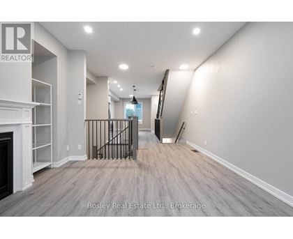 A spacious room with a fireplace and a staircase with a metal railing.
