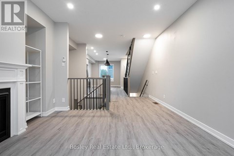A spacious room with a fireplace and a staircase with a metal railing.