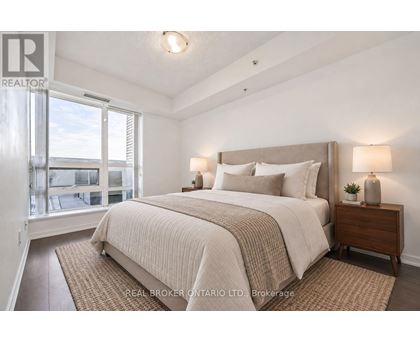 A bedroom with a large bed and a window overlooking a balcony.