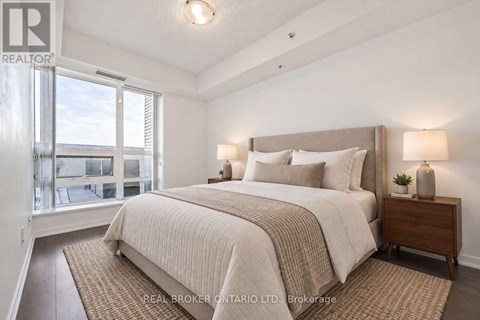 A bedroom with a large bed and a window overlooking a balcony.