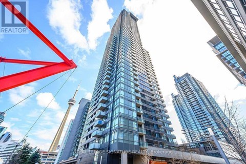 A tall building with many windows stands in front of other buildings.