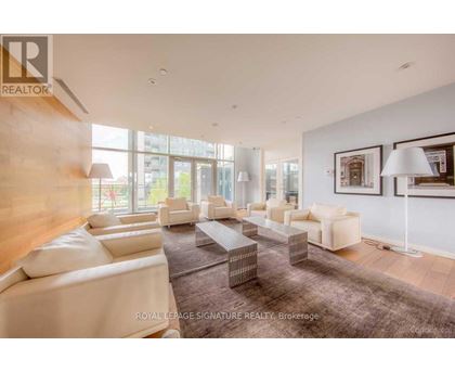A spacious living room with white furniture and a large window.
