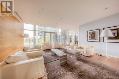 A spacious living room with white furniture and a large window.