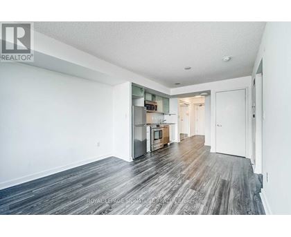 A spacious room with wooden flooring and white walls.