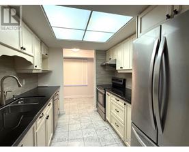 A kitchen with a refrigerator, sink, and cabinets.