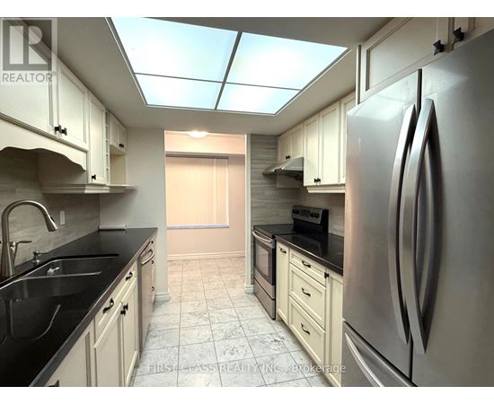 A kitchen with a refrigerator, sink, and cabinets.