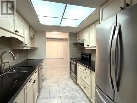 A kitchen with a refrigerator, sink, and cabinets.