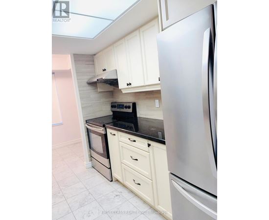 A kitchen with a stainless steel refrigerator and white cabinets.