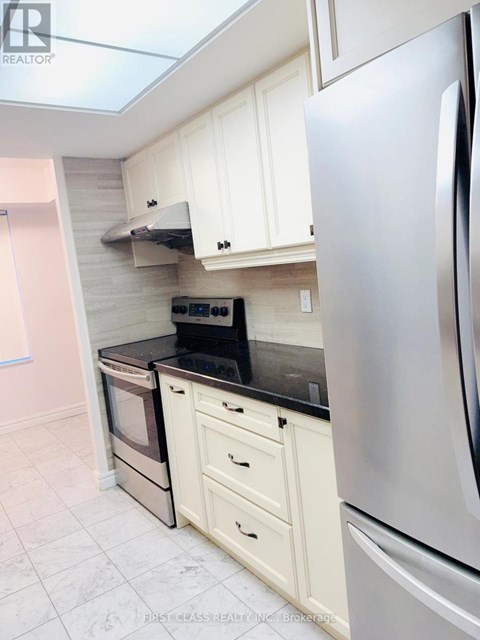 A kitchen with a stainless steel refrigerator and white cabinets.