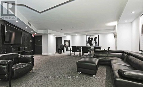 A living room with black leather furniture and a flat screen TV.