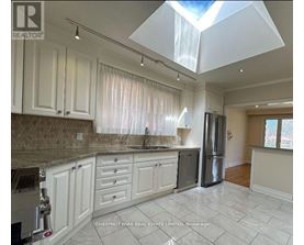 A kitchen with white cabinets and a marble countertop.