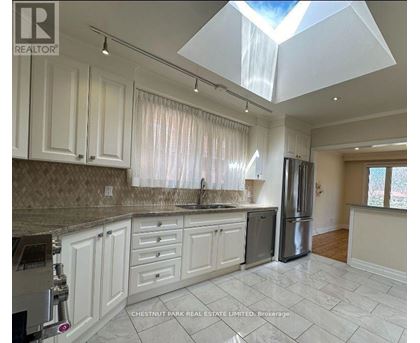 A kitchen with white cabinets and a marble countertop.