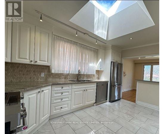 A kitchen with white cabinets and a marble countertop.
