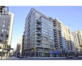 A large, modern building with many windows is in the middle of a city street.