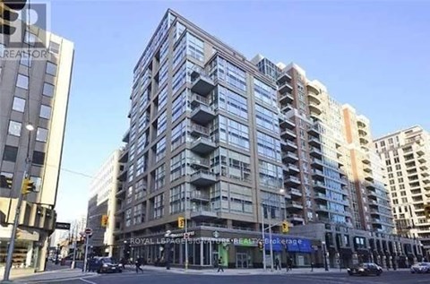 A large, modern building with many windows is in the middle of a city street.