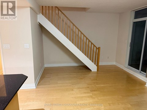 A room with a wooden floor and a staircase.