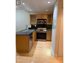A kitchen with wooden cabinets and black countertops.