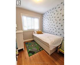 A small bedroom with a white bed and a green mat on the floor.