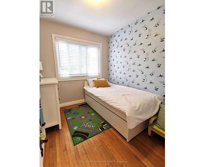 A small bedroom with a white bed and a green mat on the floor.