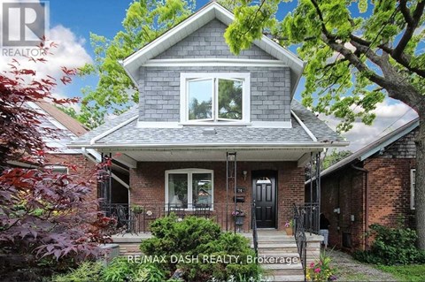 A house with a grey roof and a black door is surrounded by greenery.