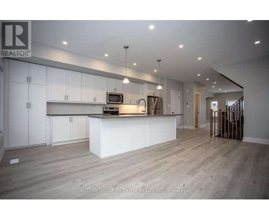 A spacious kitchen with white cabinets and a wooden floor.