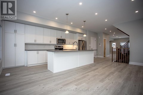 A spacious kitchen with white cabinets and a wooden floor.