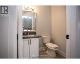 A white toilet in a bathroom with a mirror above the sink.