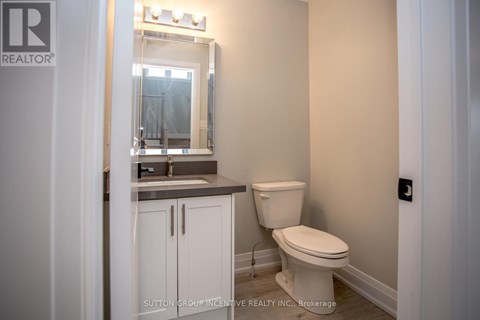 A white toilet in a bathroom with a mirror above the sink.