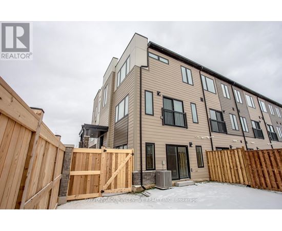 A modern two-story residential building with a wooden fence in front.