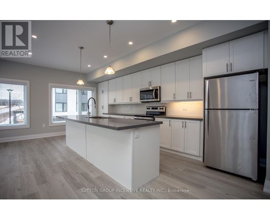 A modern kitchen with white cabinets and a stainless steel refrigerator.