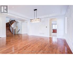 A spacious room with wooden floors and a staircase.