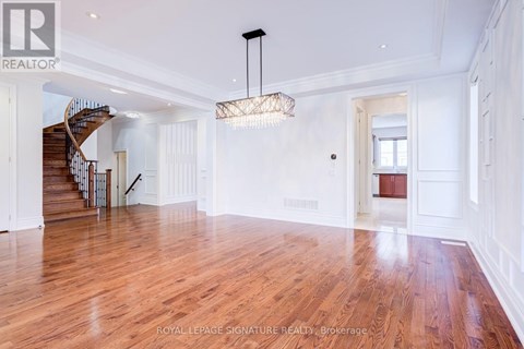 A spacious room with wooden floors and a staircase.