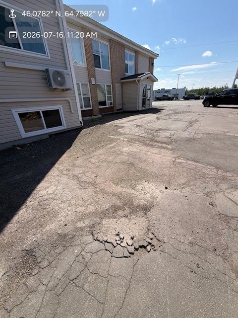 A cracked parking lot in front of a building.