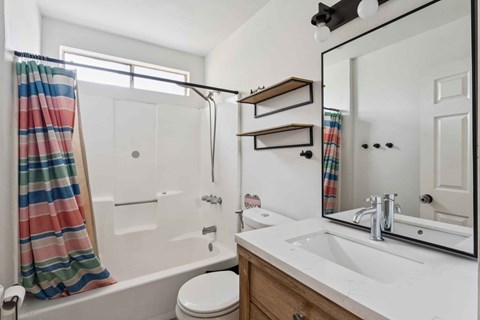 A white bathroom with a striped shower curtain.