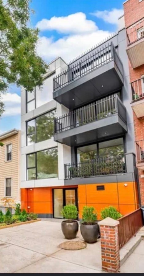 A modern two-story apartment building with a balcony on the second floor.