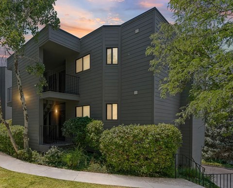 A modern house with a balcony and a tree in front.