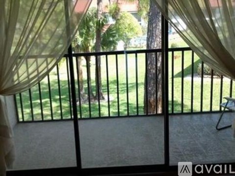 A balcony with a view of a green lawn and trees.