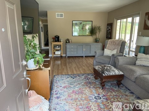 A living room with a grey couch, a wooden table, and a rug.