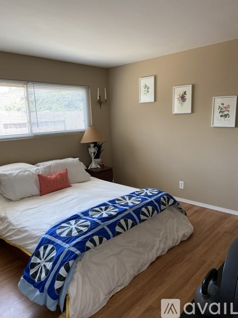 A bedroom with a bed, pillows, a lamp, and pictures on the wall.