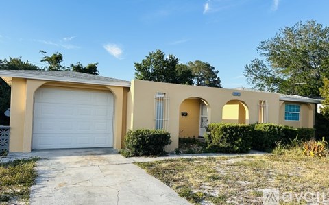 A two-story house with a white garage door and a driveway leading to it.