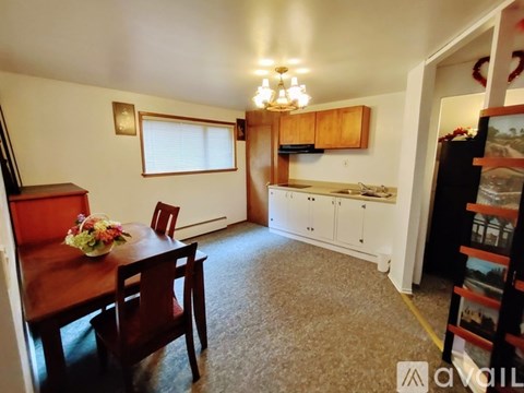 A kitchen with a table and chairs in the foreground and a fridge in the background.