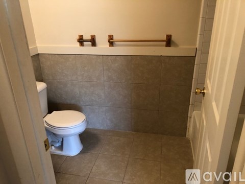 A white toilet sits in a bathroom with grey tiles.