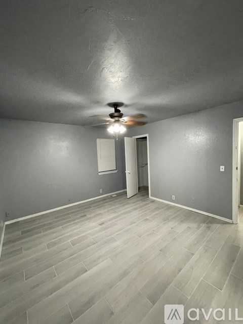 A room with a ceiling fan and light fixture, and a door.